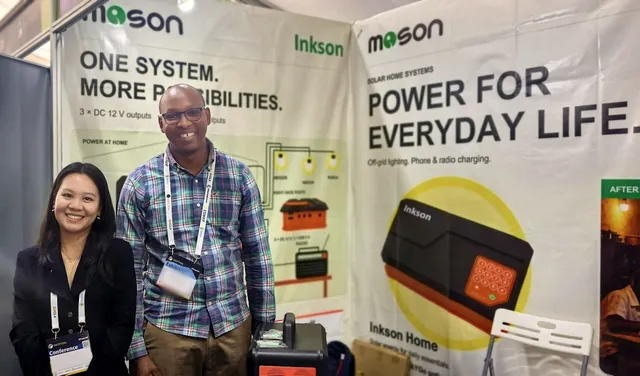 A visitor with a member of the MOSON team in front of the MOSON banners at booth 32