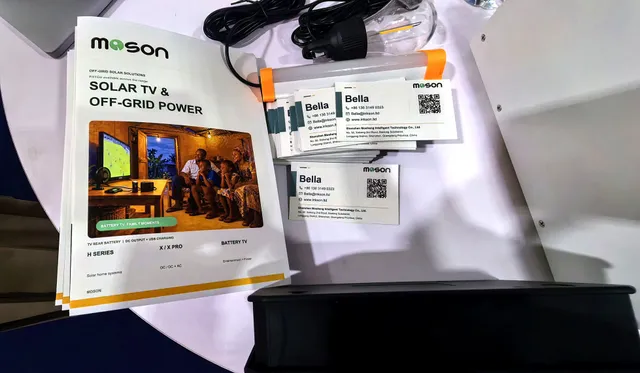 The MOSON brochure "Solar TV & Off-Grid Power" and business cards at booth 32